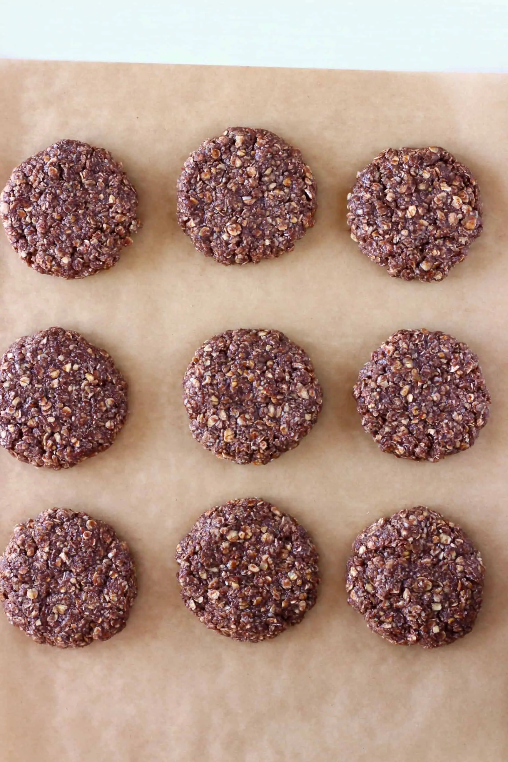 Nine gluten-free vegan chocolate no-bake cookies on a sheet of baking paper