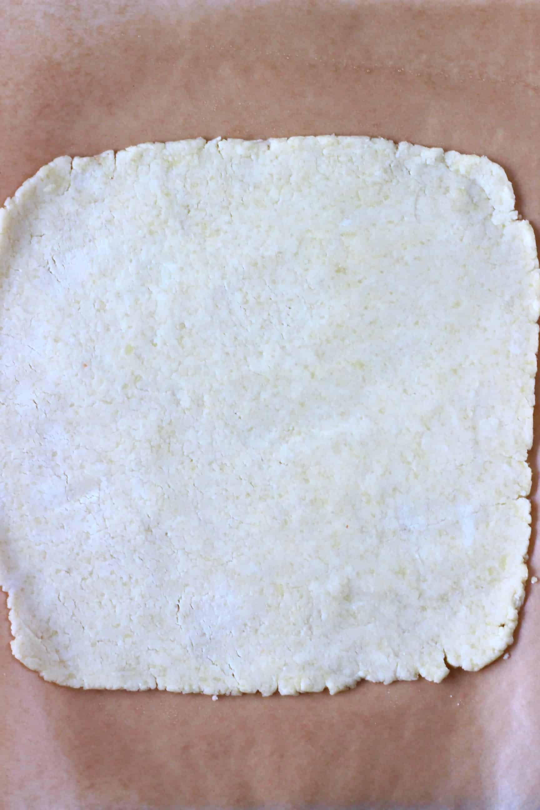 A square of raw gluten-free vegan pastry dough on a sheet of baking paper