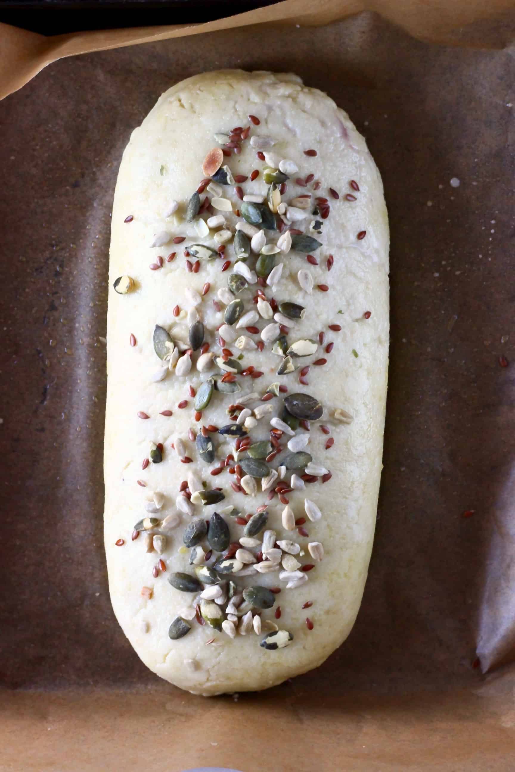 This Vegan Wellington is crispy and flaky, rich and hearty and so full of flavour! A seriously satisfying plant-based showstopper - it's perfect for Christmas, Thanksgiving, Easter and everything in between! Vegetarian, gluten-free, dairy-free, egg-free. #vegan #vegetarian #christmas #thanksgiving #dairyfree #glutenfree #rhiansrecipes Raw vegan wellington sprinkled with mixed seeds on a baking tray