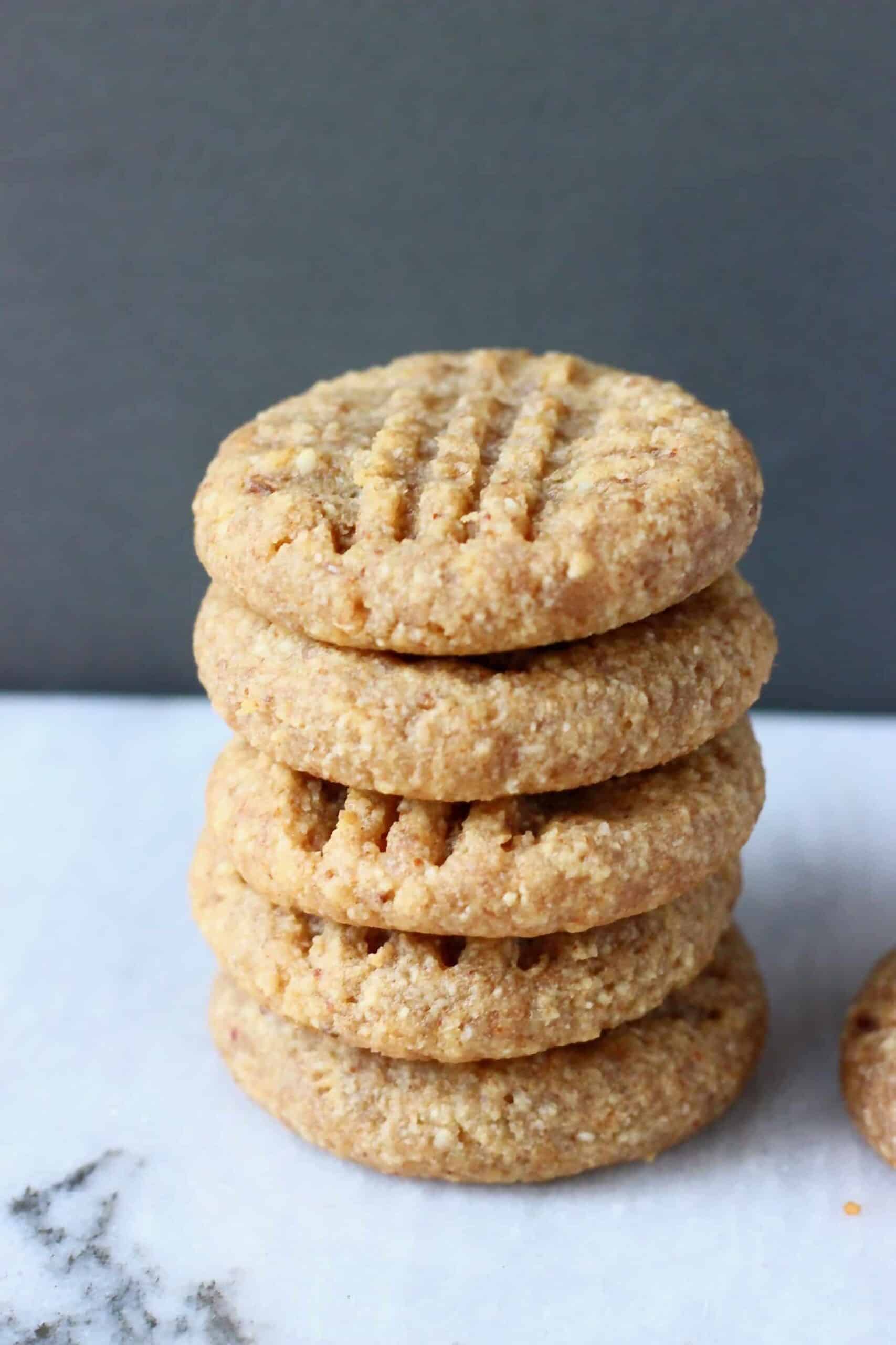 Photo of a stack of five peanut butter cookies on a marble slab against a grey background