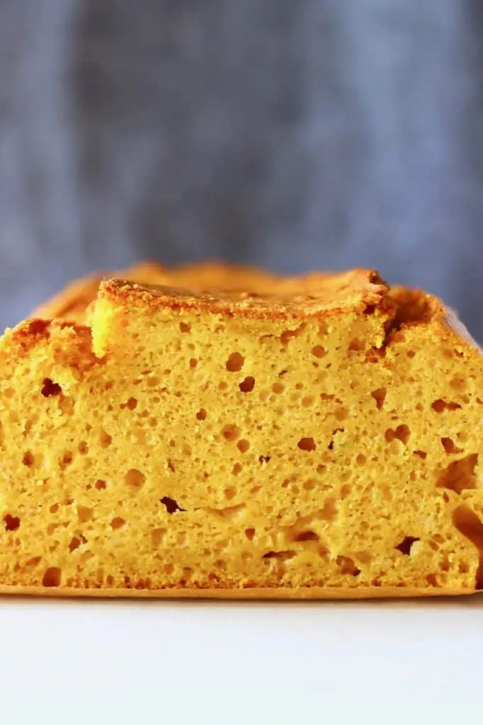 Photo of a sliced loaf of pumpkin bread against a grey background