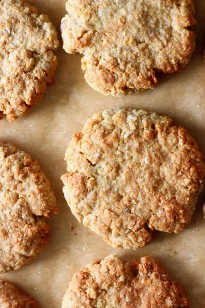 Six golden brown cookies against a sheet of brown baking paper