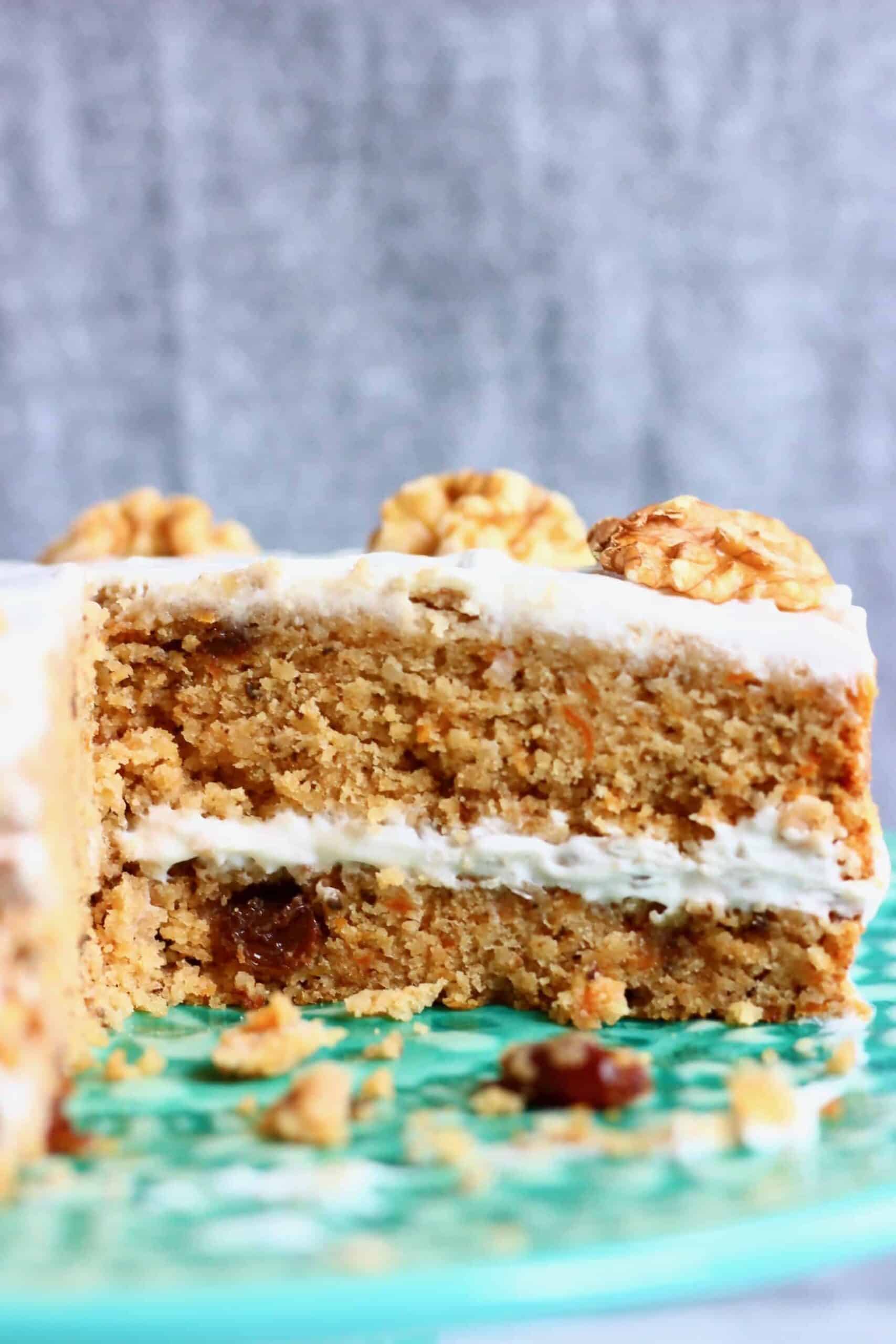 Photo of a sliced carrot cake on a green cake stand with a grey background