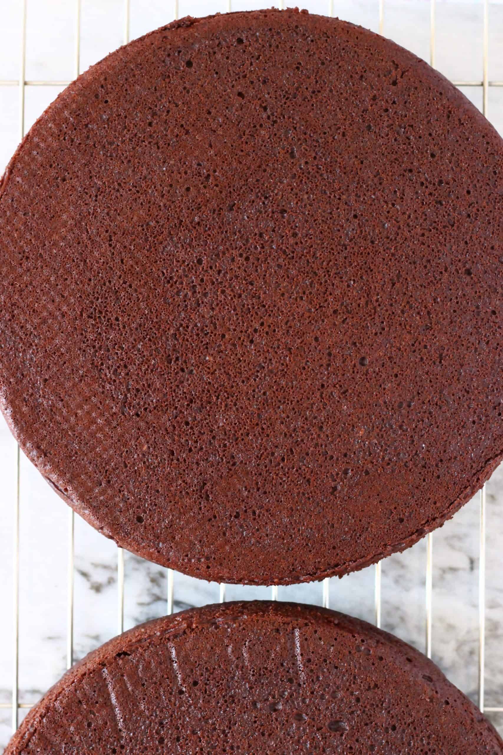 Two gluten-free vegan chocolate sponge cakes on a wire rack 