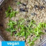 Mushroom risotto topped with rocket in a silver pan against a grey background