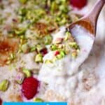 Rice pudding in a grey rectangular baking dish topped with chopped pistachios and fresh raspberries
