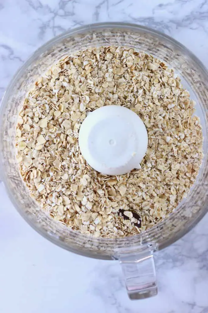 Oats in a food processor against a marble background