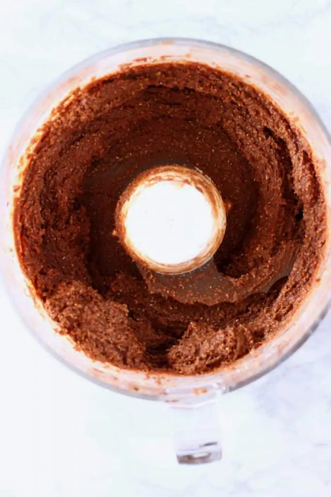 Chocolate brownie mixture in a food processor against a marble background
