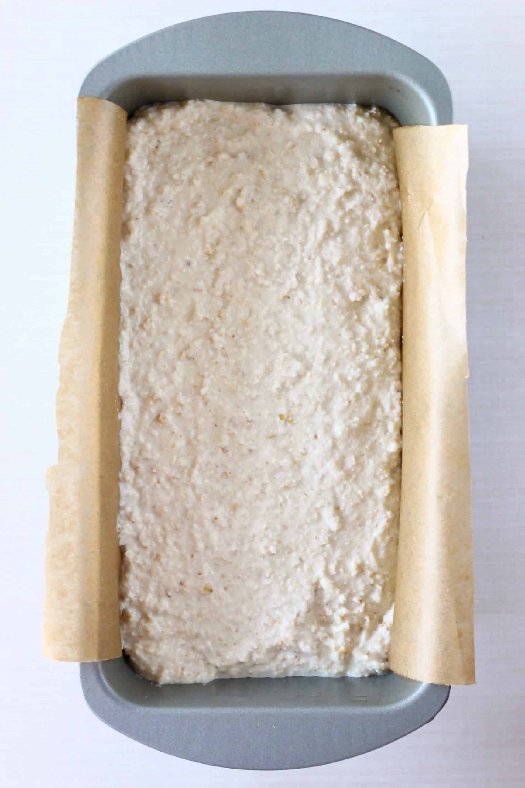 This Gluten-Free Vegan Oat Bread is soft on the inside, crusty on the outside, nutty, slightly chewy, and unbelievably easy to make! It's also no-knead, yeast-free and completely free from sugar! It's made in one bowl using simple ingredients, slices well and is perfect for making sandwiches! Dairy-free, soy-free, oil-free, corn-free, egg-free and nut-free optional. #rhiansrecipes #baking #bread #glutenfree #yeastfree #vegan #dairyfree #eggfree Gluten-free vegan oat bread dough in a loaf tin lined with baking paper