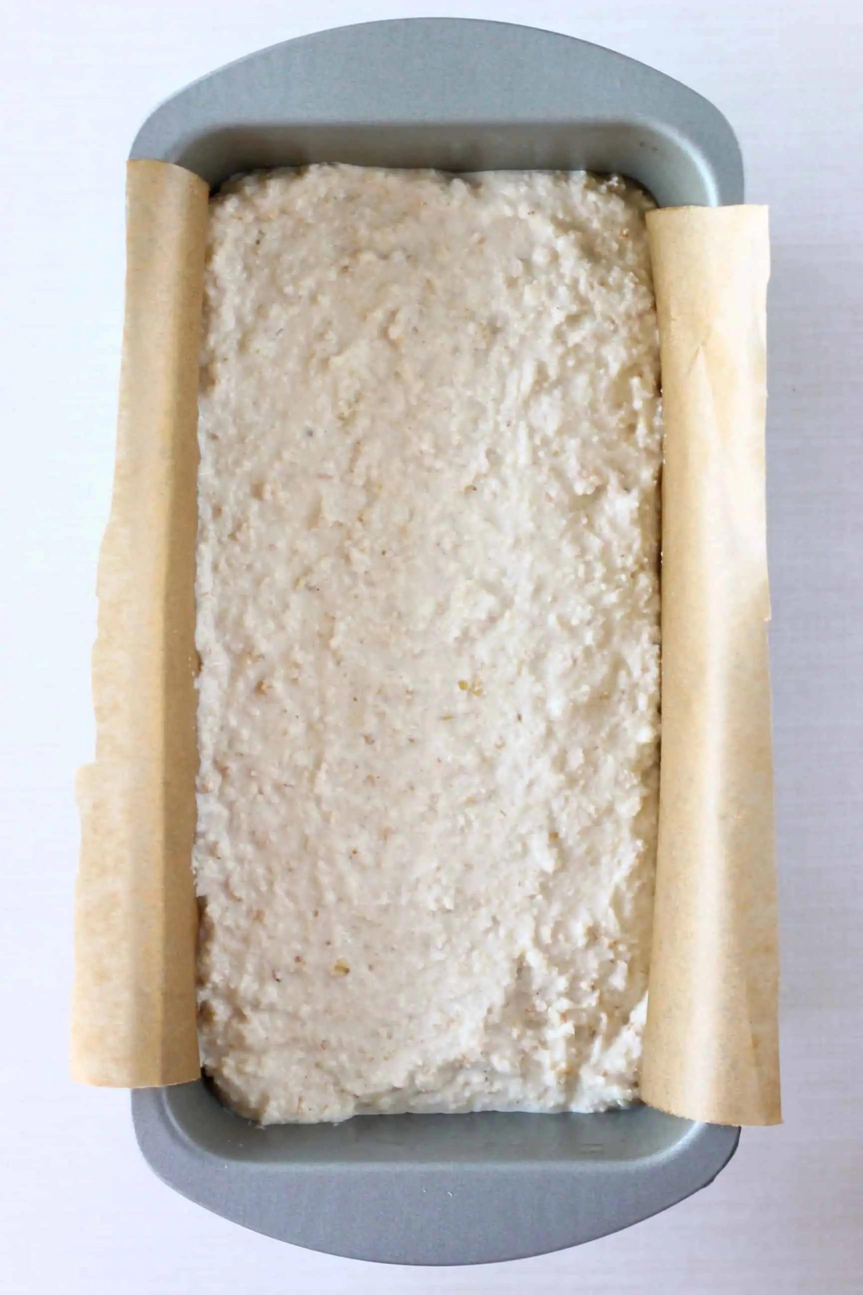 Gluten-free vegan oat bread dough in a loaf tin lined with baking paper 