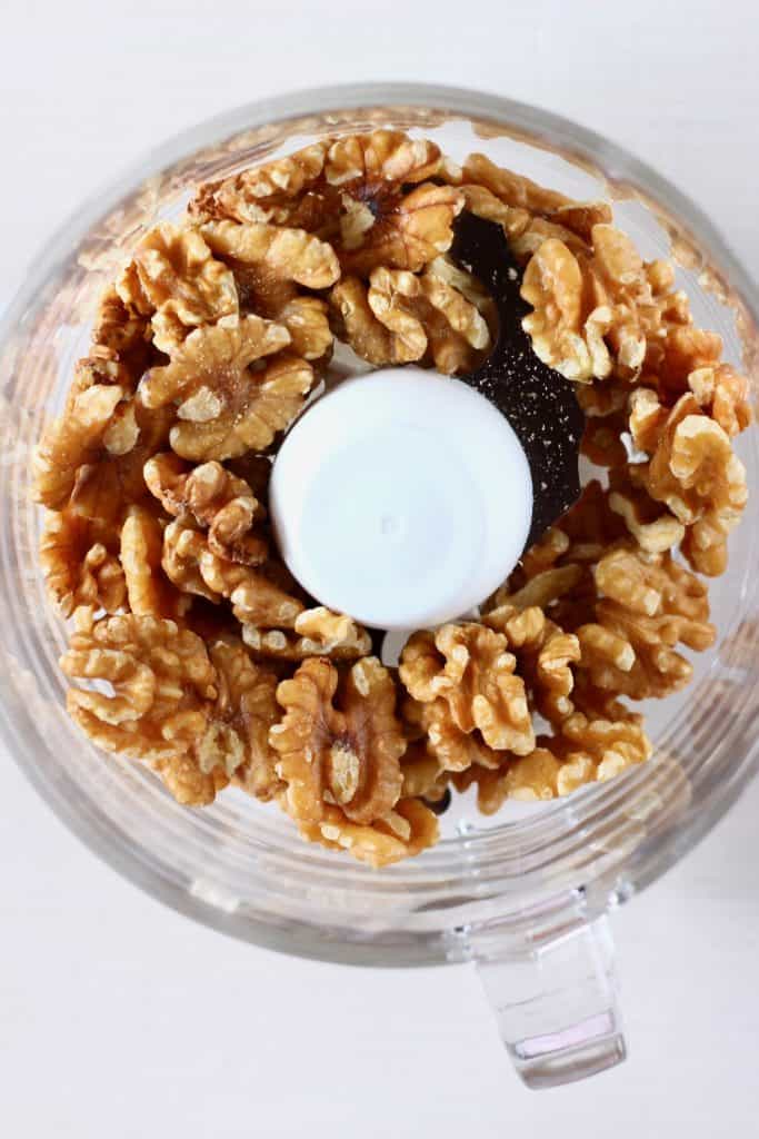 Walnuts in a food processor against a white background