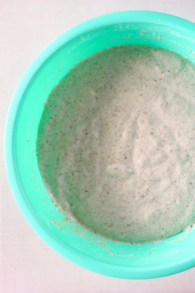 White bread batter in a green bowl against a white background