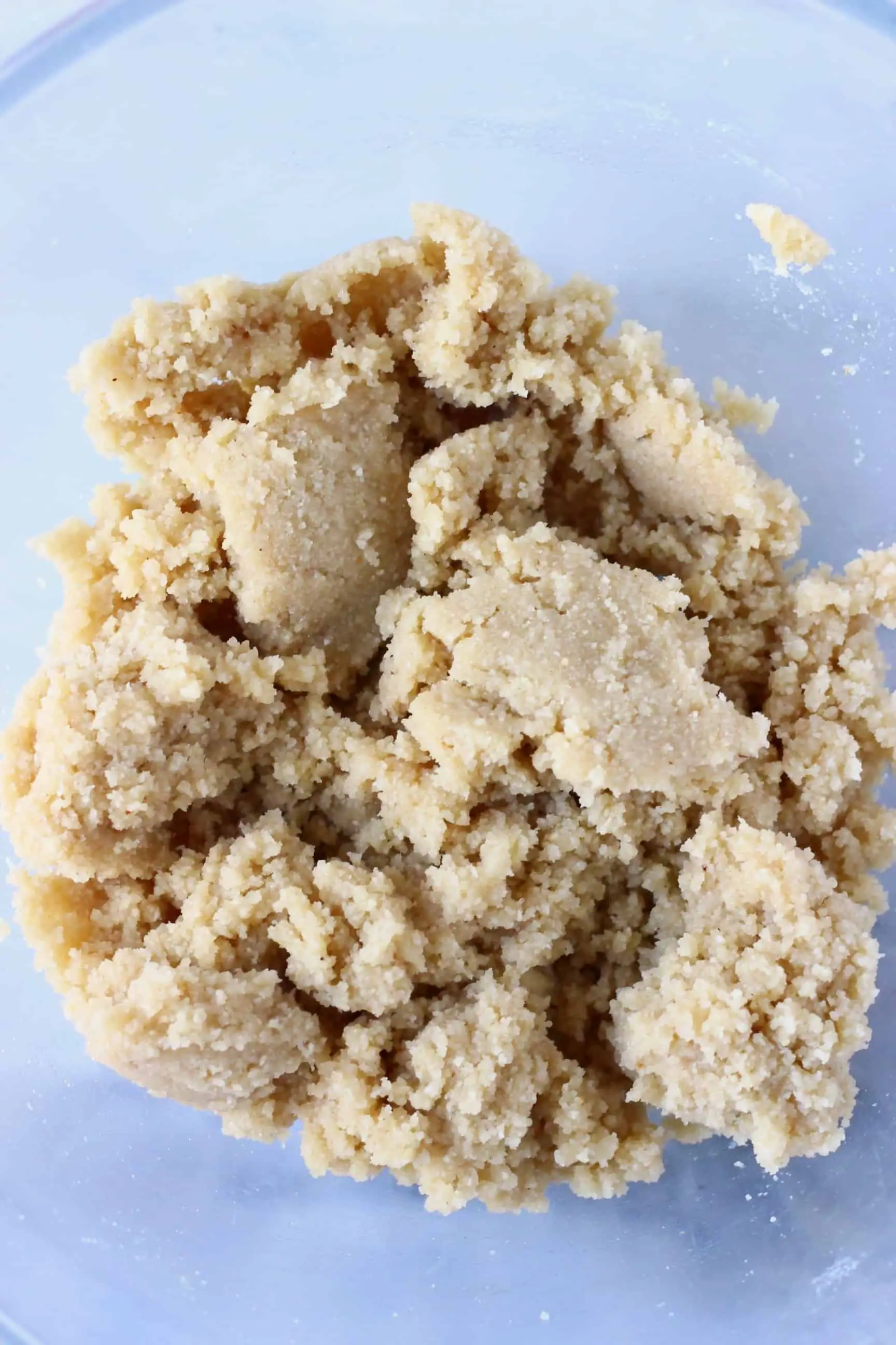 Raw vegan shortbread cookie dough in a mixing bowl against a marble background