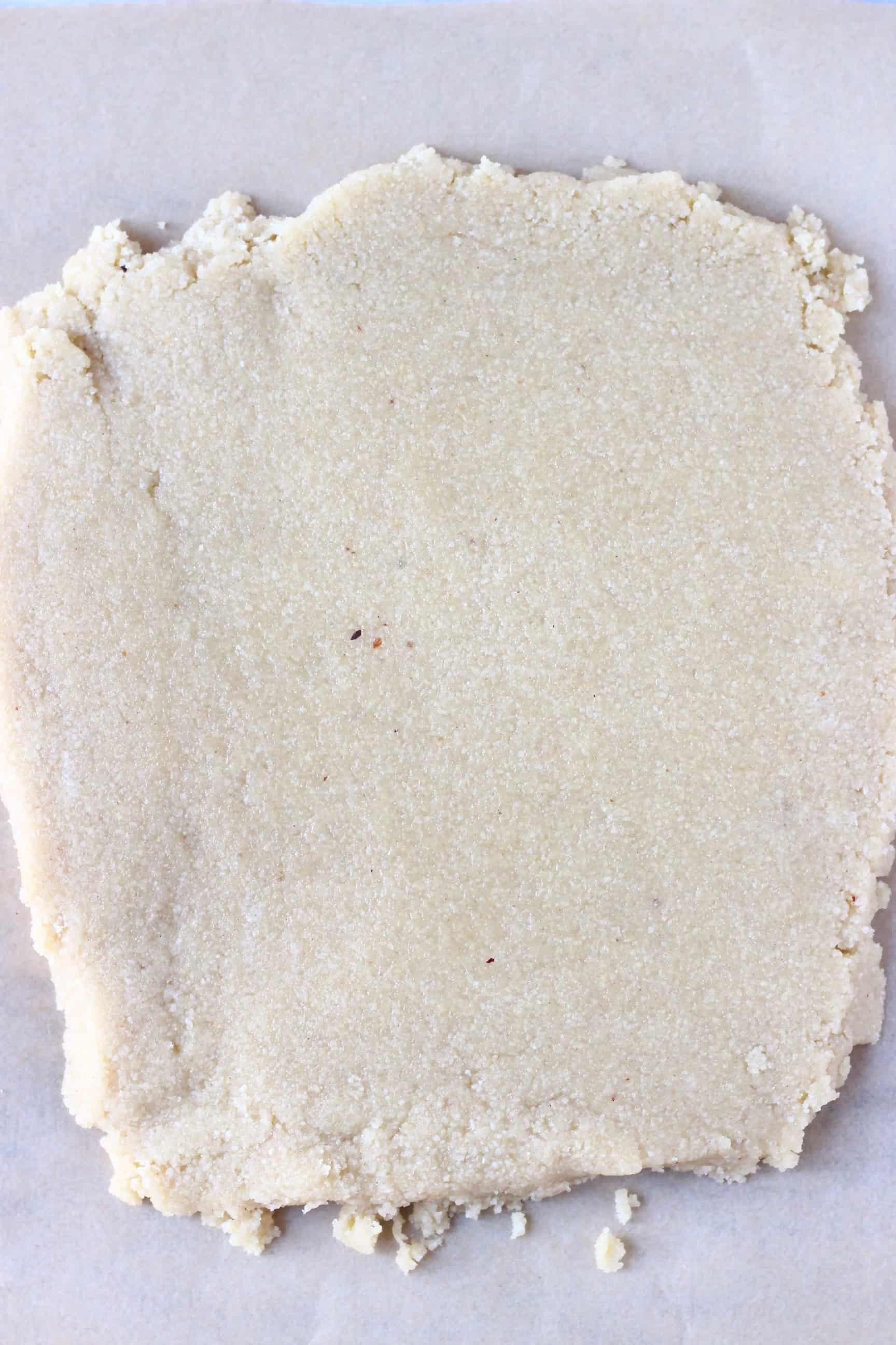 A square of raw vegan shortbread cookie dough rolled out on baking paper