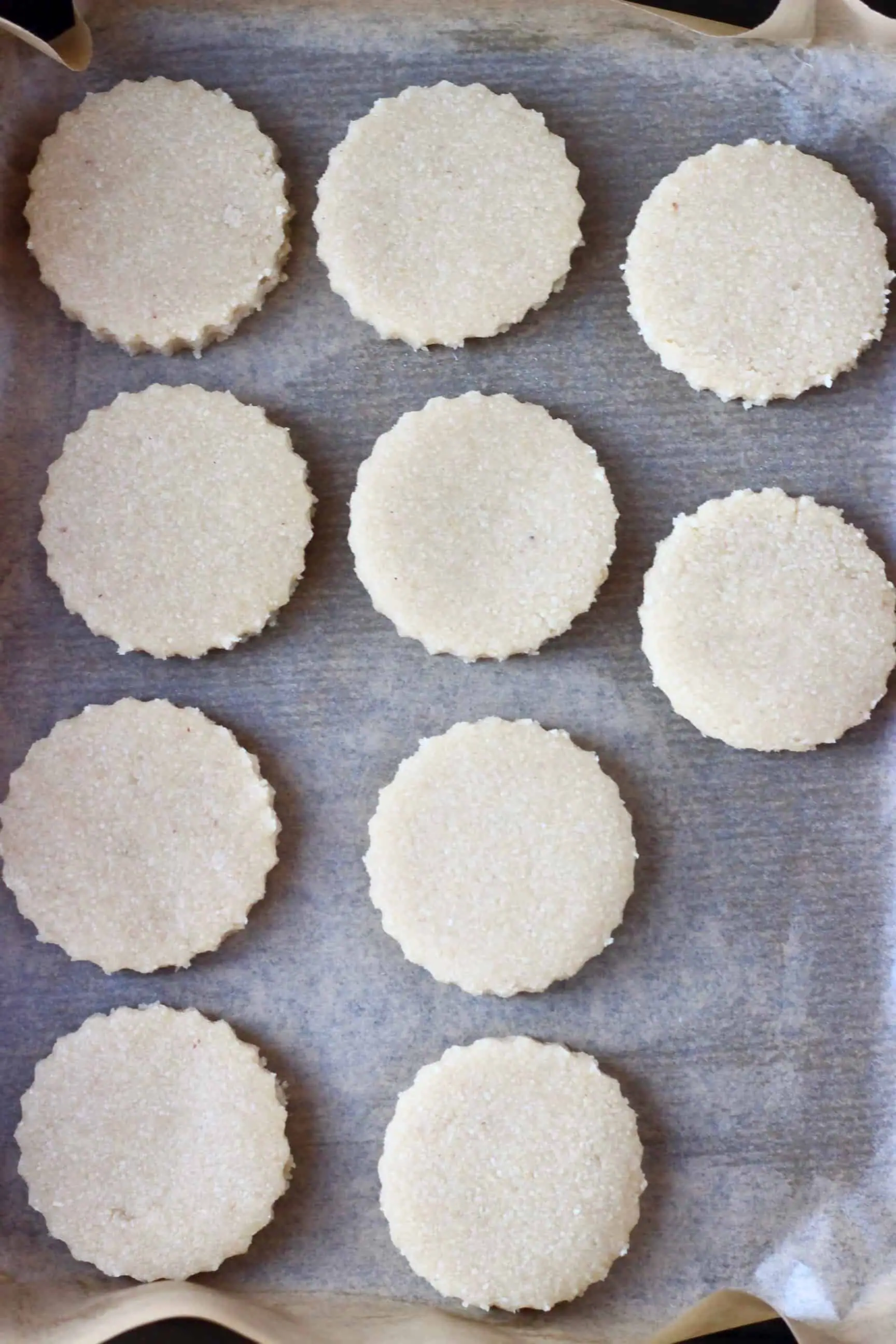 Ten circular raw vegan shortbread cookies on baking paper