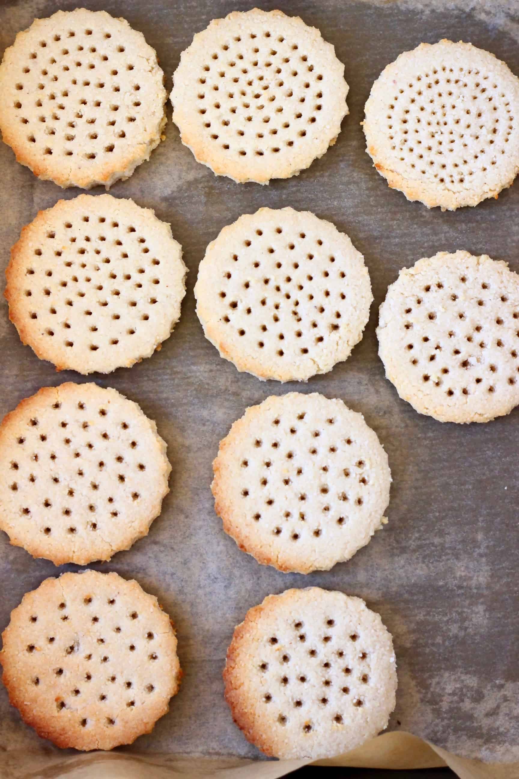 Ten shortbread cookies with holes cut out on a baking tray