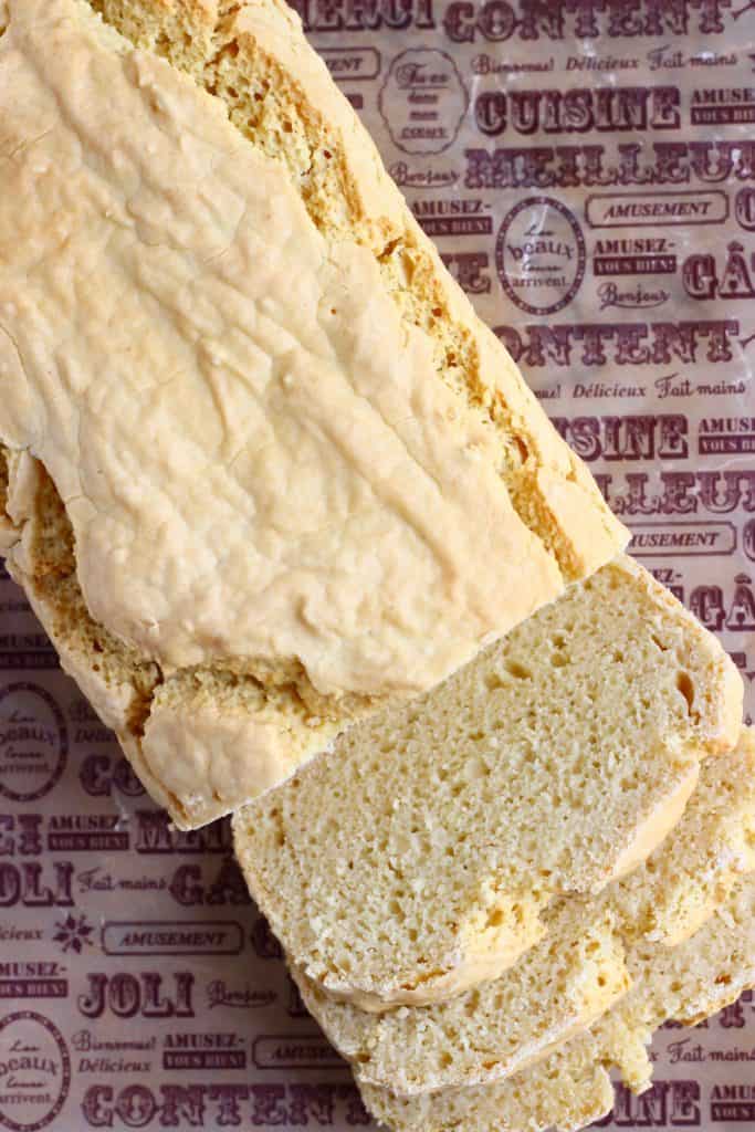 Photo taken from above of a sliced loaf of bread on a piece of brown baking paper