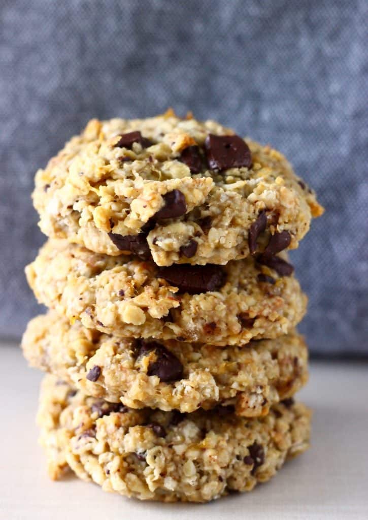 Photo of four chocolate chip cookies stacked up on top of each other against a grey background