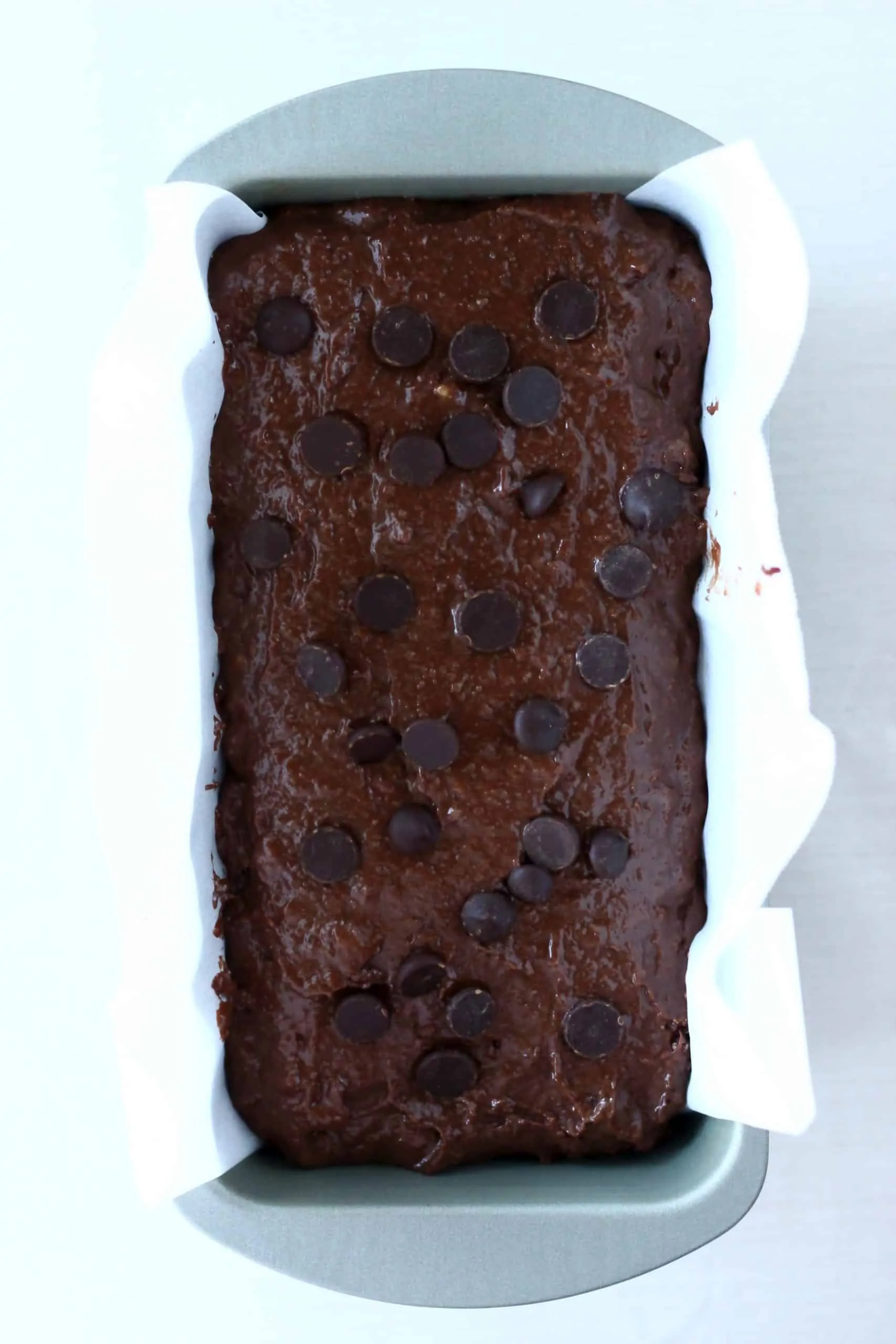 Raw gluten-free vegan chocolate banana bread batter in a loaf tin topped with chocolate chips