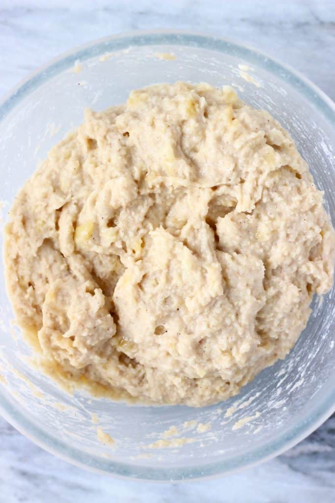 Banana pancake batter in a glass mixing bowl against a marble background