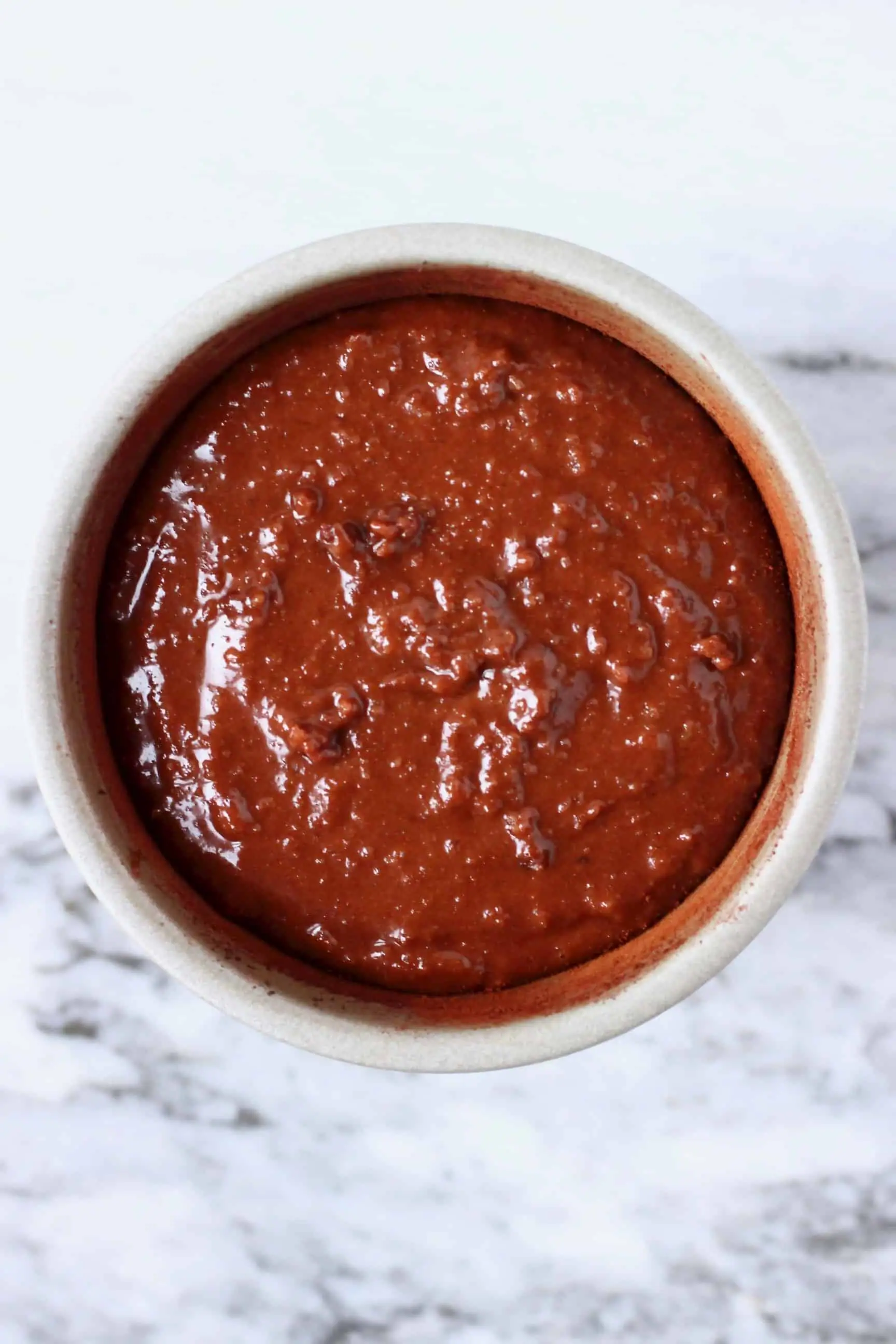 A small pudding tin filled with raw gluten-free vegan chocolate lava cake batter