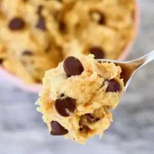 Vegan cookie dough with chocolate chips in a bowl with a spoon lifting up a mouthful