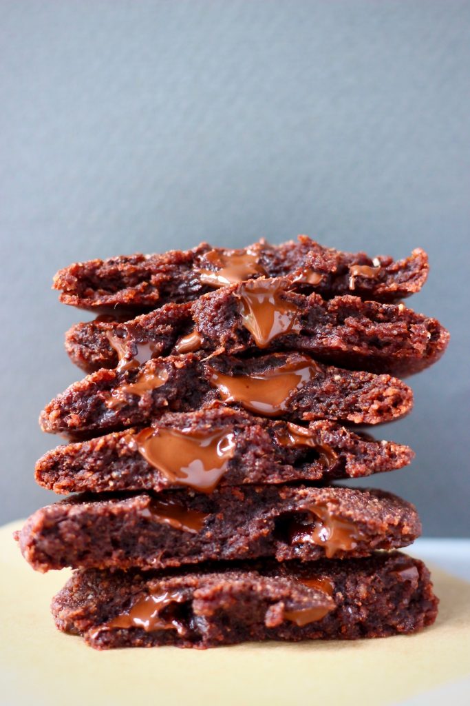 Photo of a stack of six chocolate cookies on a sheet of brown baking paper against a grey background