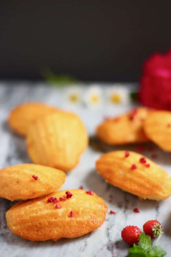 Seven madeleines on a marble surface against a black background