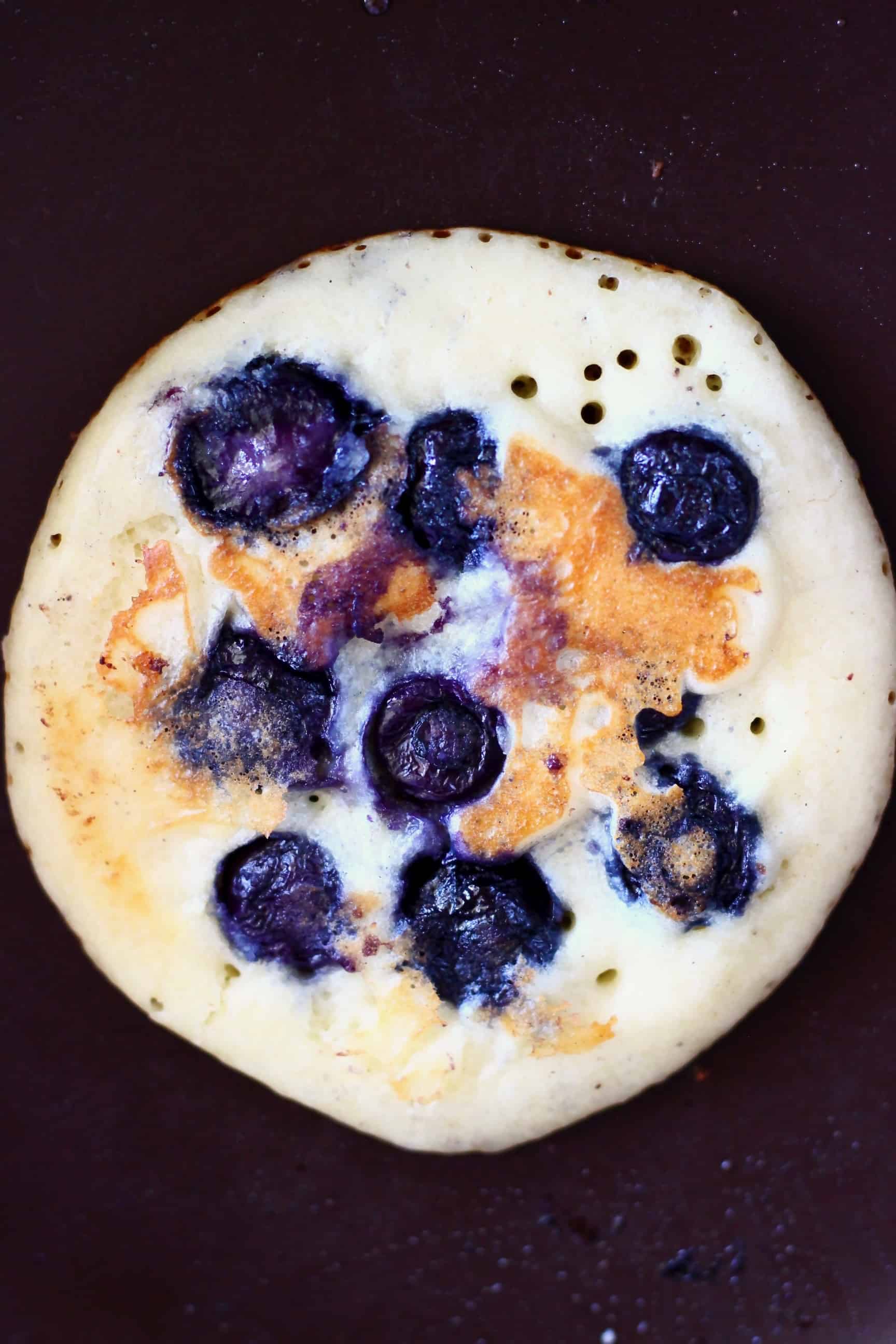 A vegan blueberry pancake in a frying pan