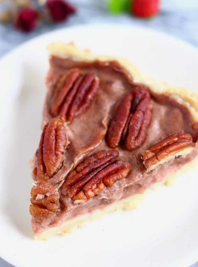 Photo of a slice of pecan pie on a white plate against a marble background