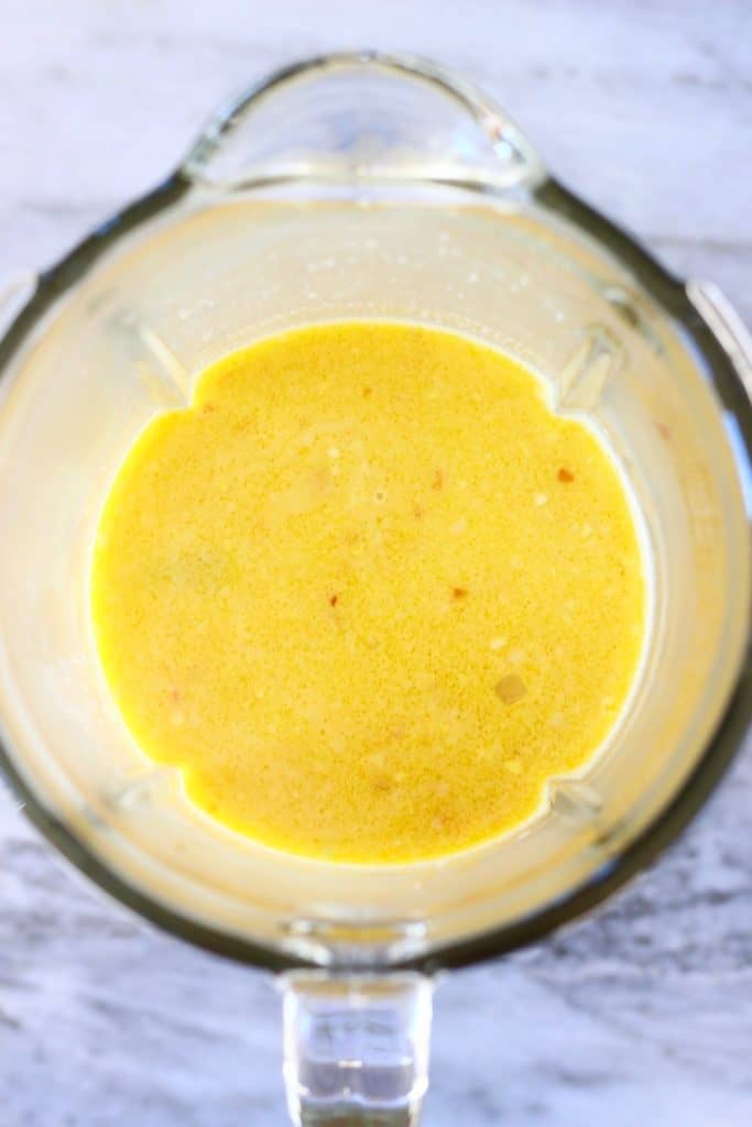 Yellow soup in a glass blender against a marble background