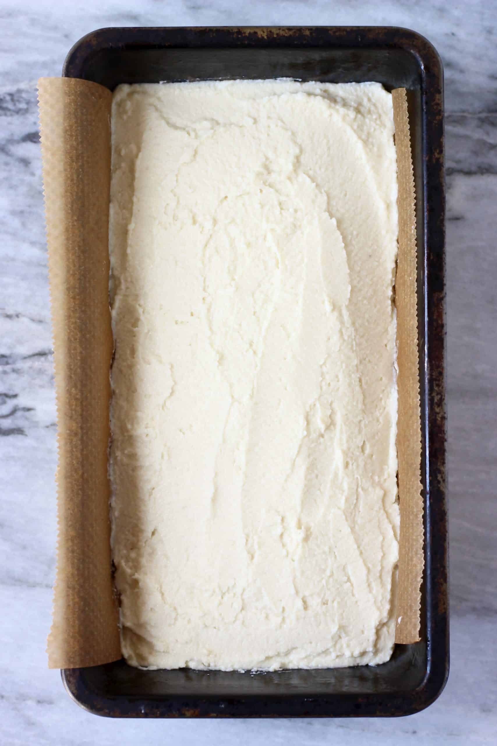 Raw coconut flour bread batter in a loaf tin lined with baking paper