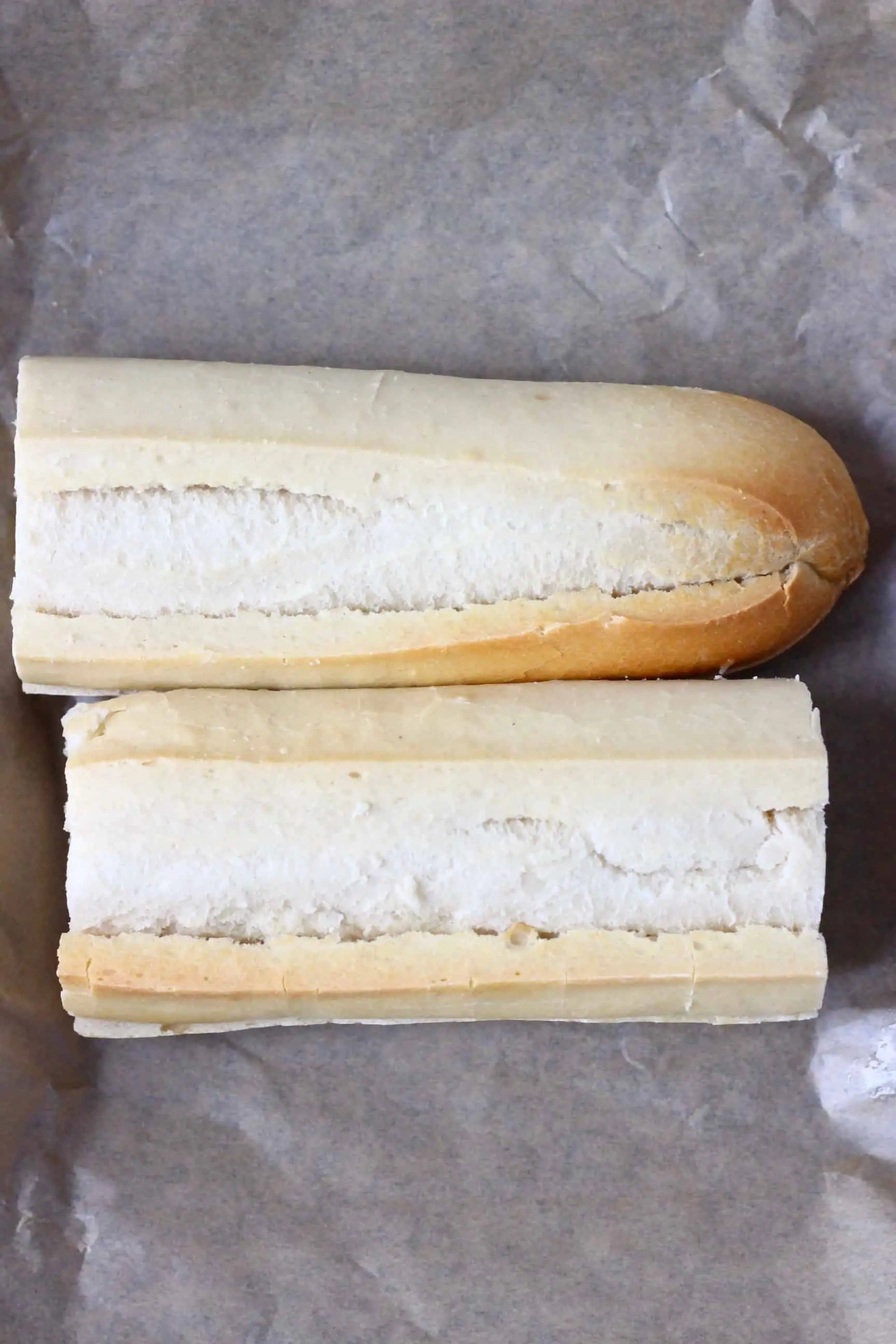 Twi white baguette halves on a sheet of baking paper