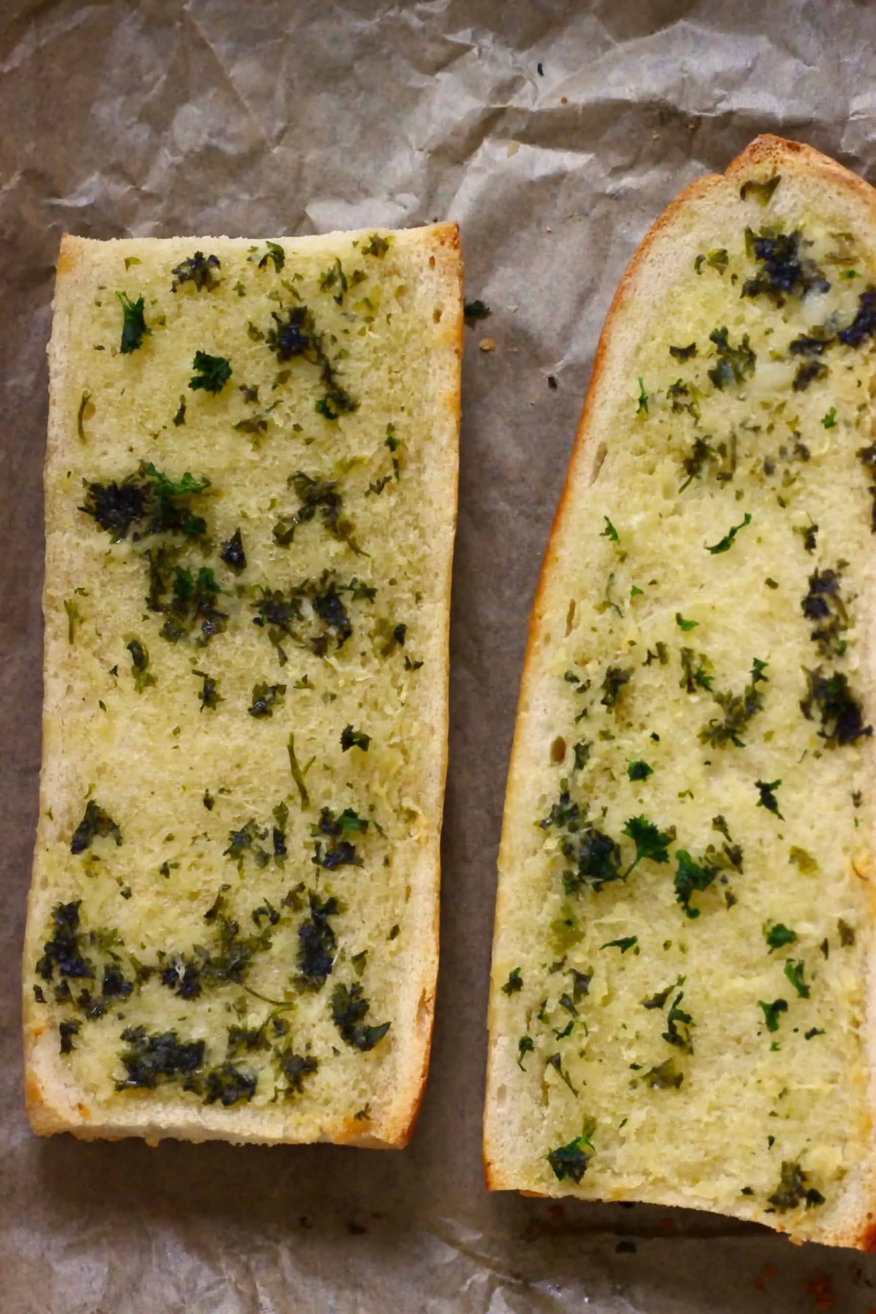 Two pieces of vegan garlic bread on a sheet of baking paper