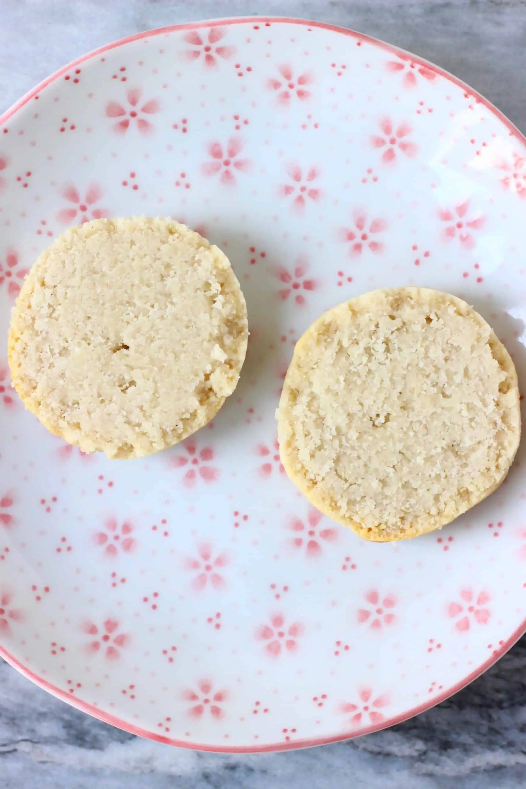 Two gluten-free vegan scone halves on a white plate with pink flowers 