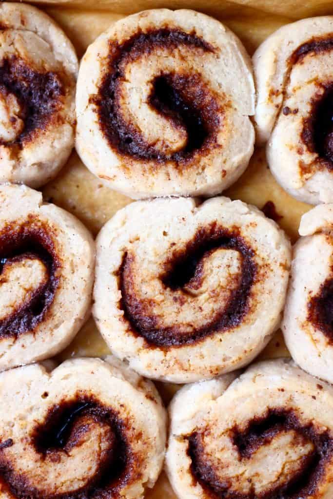 Photo of nine cinnamon rolls against a sheet of brown baking paper