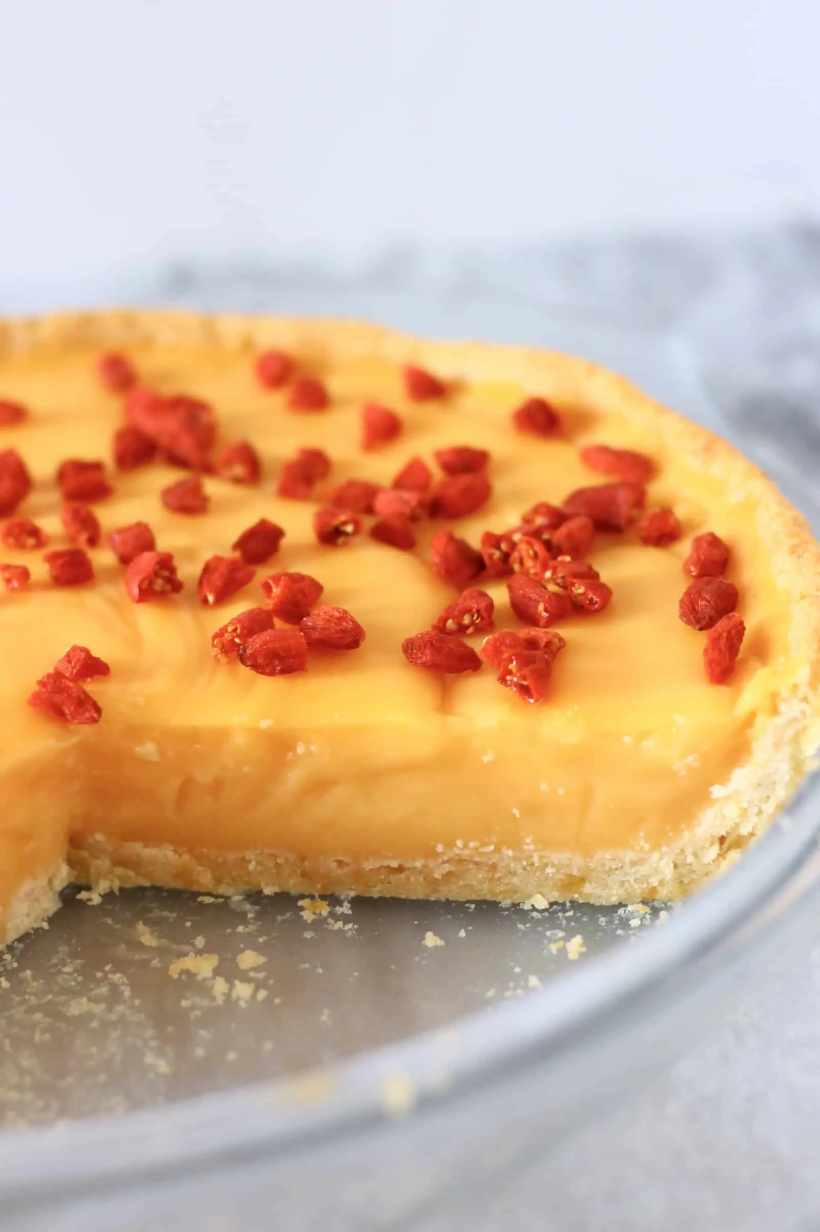 Lemon tart topped with goji berries in a pie dish