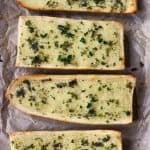 Four pieces of garlic bread on a sheet of brown baking paper