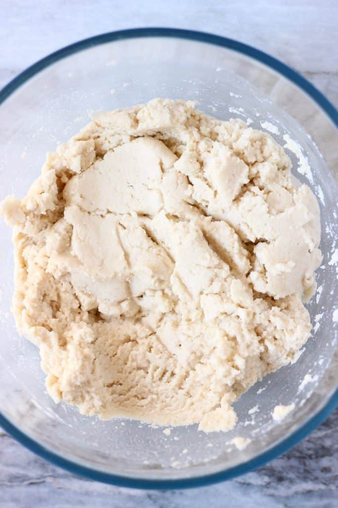 Bagel dough in a glass mixing bowl against a marble background