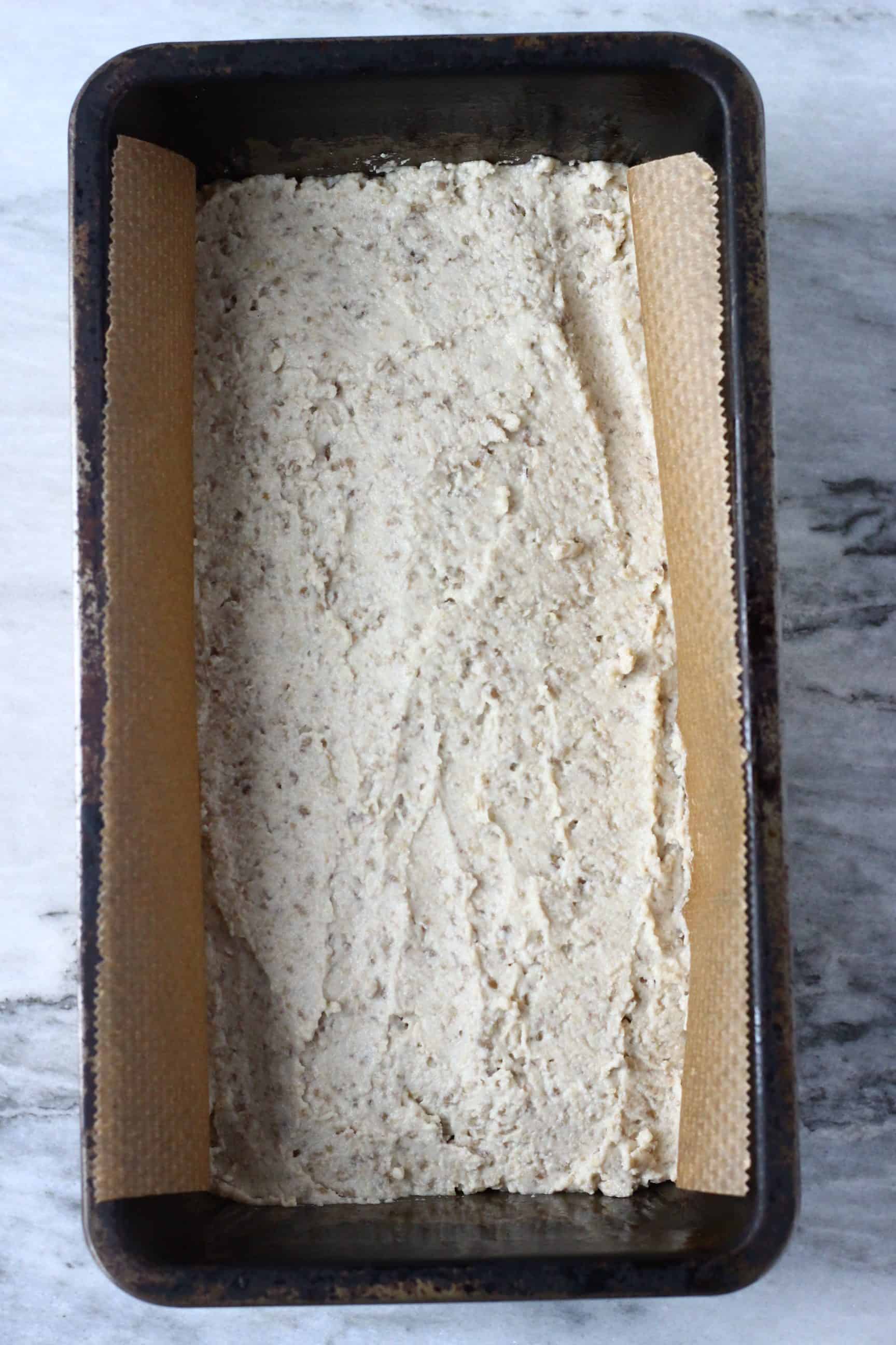 Raw sunflower seed bread batter in a loaf tin lined with baking paper