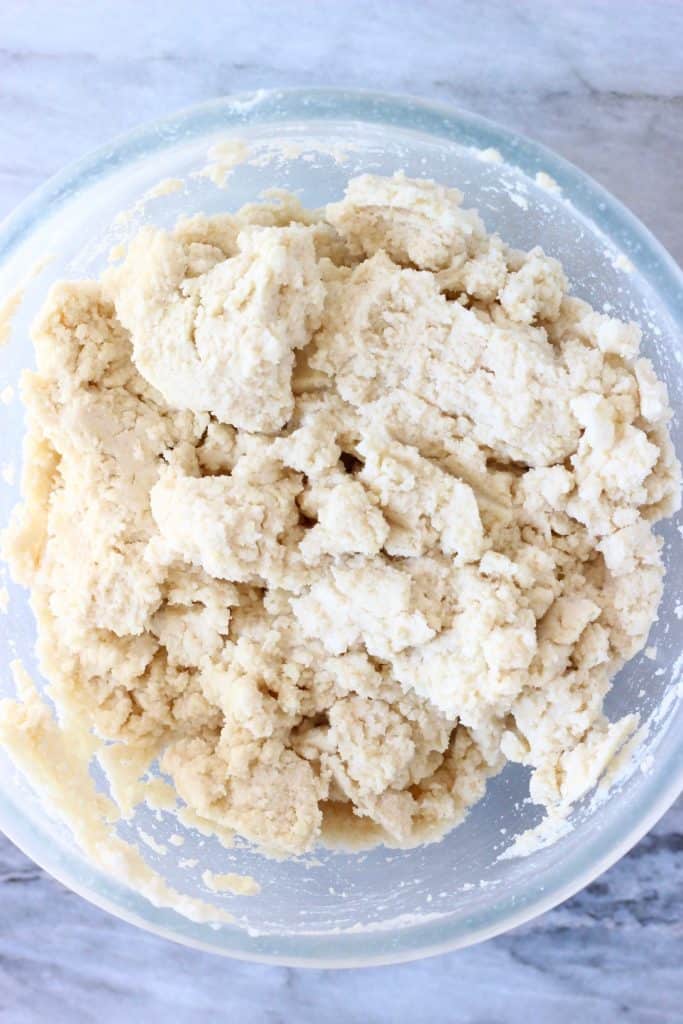 Raw bread dough in a glass mixing bowl against a marble background