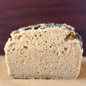 A sliced loaf of sunflower seed bread on a sheet of baking paper