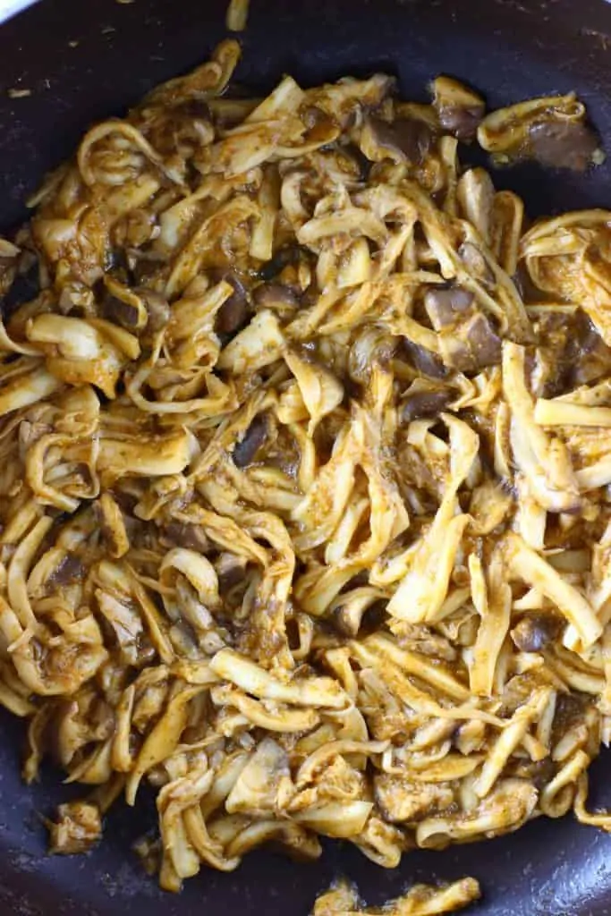 Shredded mushrooms with brown sauce in a black frying pan