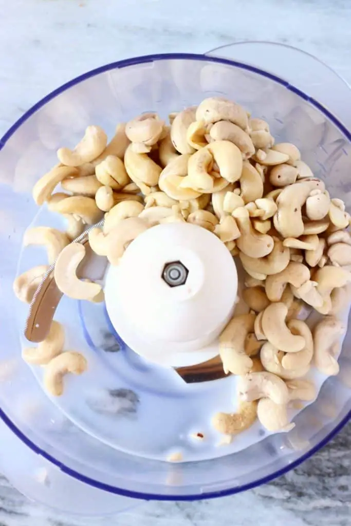 Photo of cashew nuts in a food processor against a marble background