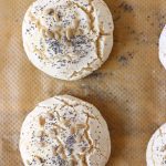 Two bread rolls topped with sunflower and poppy seeds on a sheet of brown baking paper