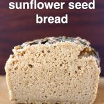 A sliced loaf of bread on a sheet of brown baking paper against a dark brown background