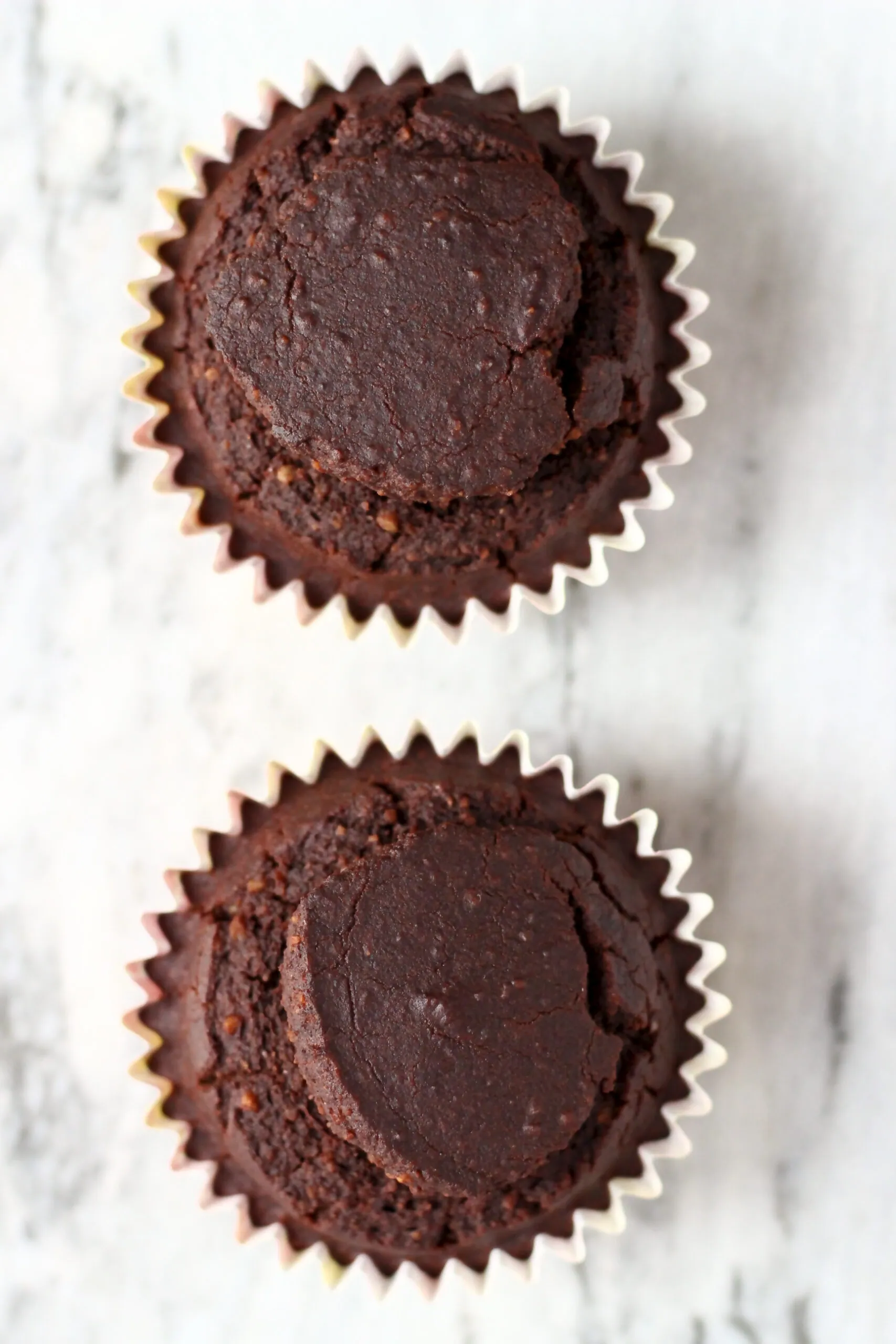 Two baked gluten-free vegan chocolate cupcakes in cupcake cases