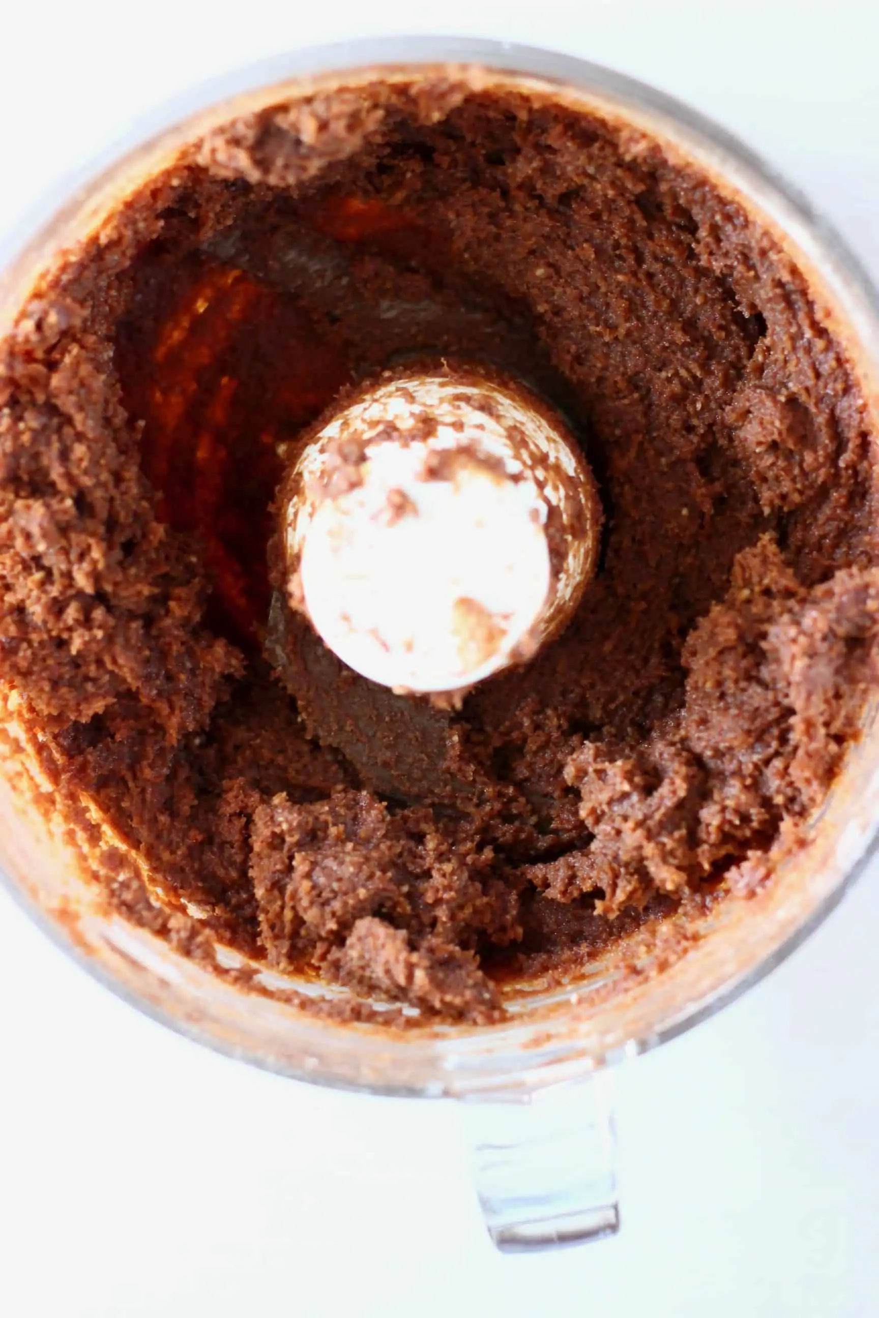 Vegan protein ball mixture in a food processor against a white background