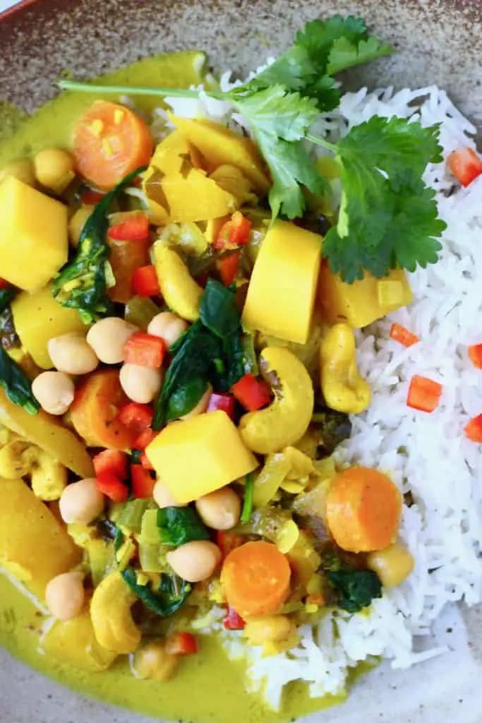 Chickpea, mango and vegetable curry with white rice on a brown plate