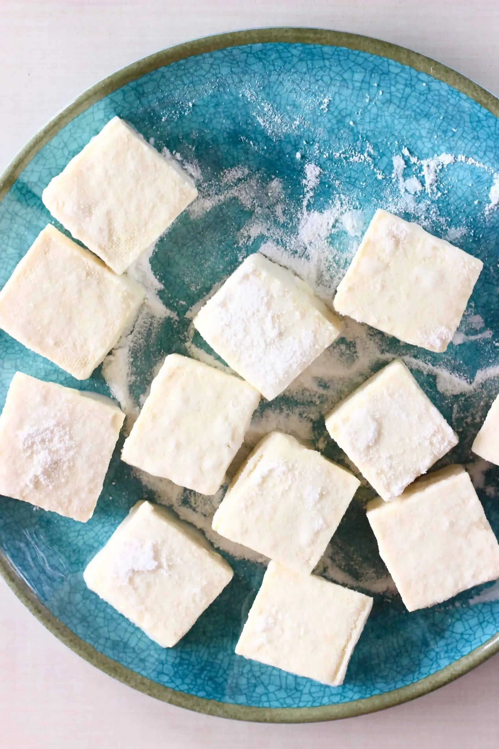 Cubes of tofu coated in cornflour on a blue plate 
